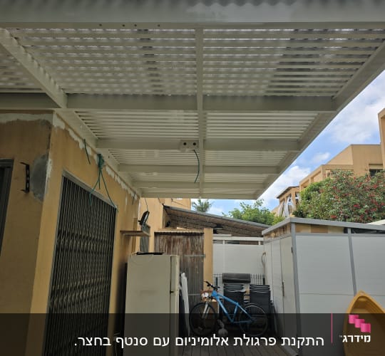 פרגולה אלומיניום בחצר עם אופניים ומקרר